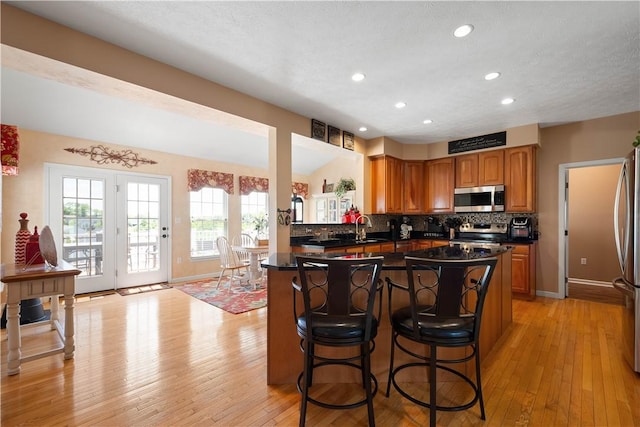 5121 Forest Ridge Dr, South Fayette, PA 15057 - kitchen featuring appliances with stainless steel finishes, light wood finished floors, dark countertops, a kitchen bar, and brown cabinets