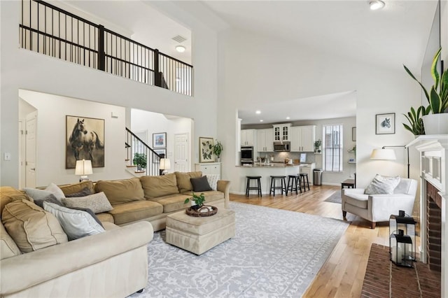 319 Buffalo Ridge Rd, Peters Twp, PA 15317 - living room with high vaulted ceiling, stairway, light wood-style flooring, a fireplace, and recessed lighting