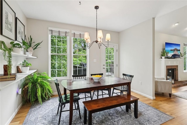 319 Buffalo Ridge Rd, Peters Twp, PA 15317 - dining area with light wood-style flooring, a brick fireplace, a chandelier, and baseboards