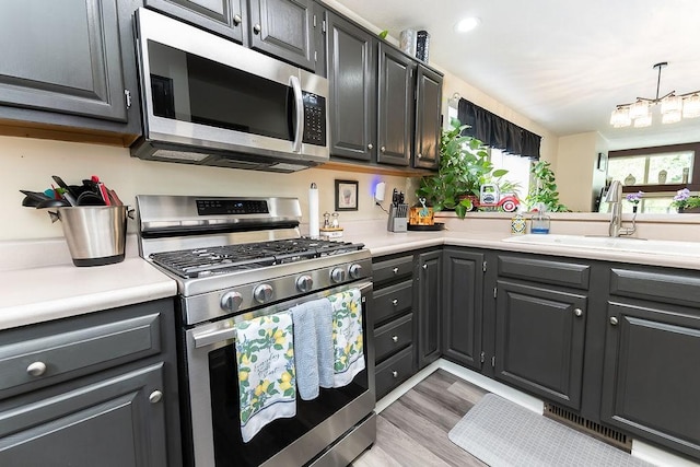 1099 Riverside Dr Unit H, Bridgewater, PA 15009 - kitchen featuring appliances with stainless steel finishes, light countertops, a sink, light wood finished floors, and a chandelier