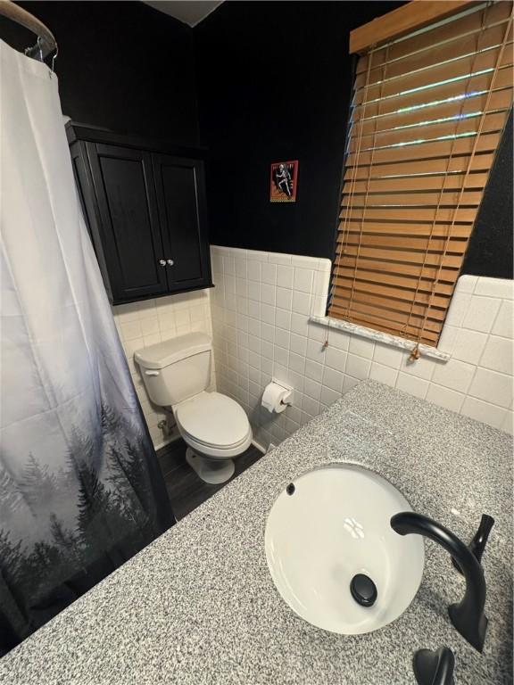 937 Freeport Rd, Natrona Hts/Harrison Twp, PA 15065 - bathroom with toilet, a sink, tile walls, curtained shower, and a wainscoted wall