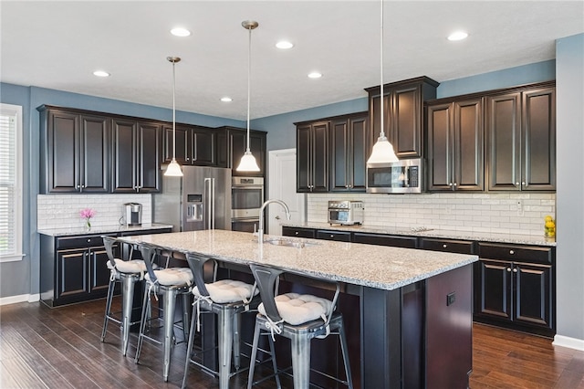1340 Diamond Ct, Upper St Clair, PA 15241 - kitchen featuring appliances with stainless steel finishes, a sink, a center island with sink, decorative backsplash, and light stone countertops