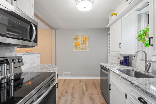 1137 Michael Dr, Baldwin Boro, PA 15227 - kitchen with appliances with stainless steel finishes, a sink, light wood-style flooring, white cabinets, and light stone counters