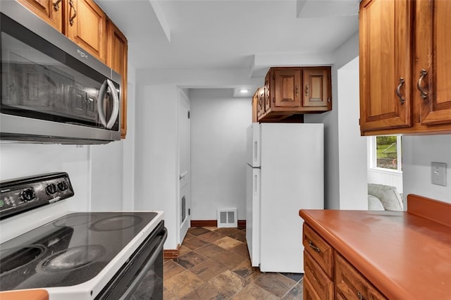 5352 Highgrove Rd, Whitehall, PA 15236 - kitchen with range with electric cooktop, stainless steel microwave, freestanding refrigerator, and brown cabinetry