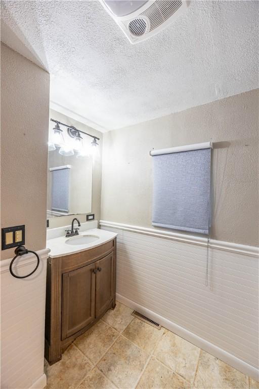 1248 Hyde Park Rd, Allegheny Twp Wml, PA 15656 - bathroom featuring vanity, a wainscoted wall, and a textured ceiling