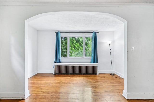 624 Frayne St, Greenfield, PA 15207 - spare room featuring radiator heating unit, arched walkways, and wood-type flooring