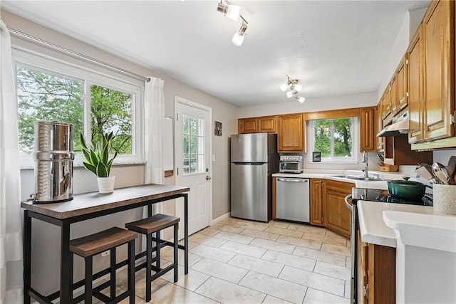 244 Burch Dr, Coraopolis, PA 15108 - kitchen featuring stainless steel appliances, a sink, brown cabinetry, light countertops, and healthy amount of natural light