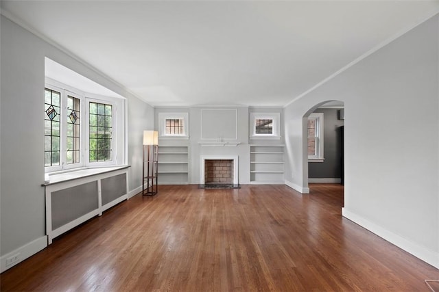 446 S Dallas Ave, Point Breeze, PA 15208 - unfurnished living room with arched walkways, wood finished floors, a fireplace, baseboards, and built in shelves