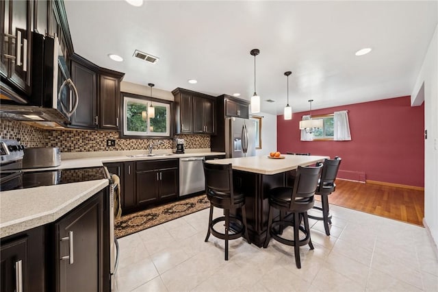 954 Illinois Ave, Braddock Hills, PA 15221 - kitchen featuring stainless steel appliances, a sink, light countertops, a breakfast bar, and tasteful backsplash