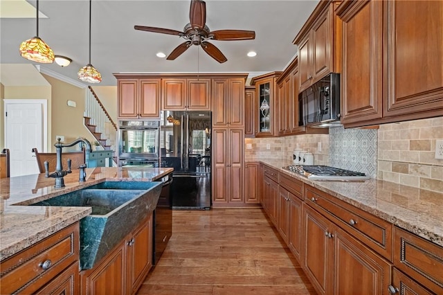 361 Patriot Ln, Economy, PA 15042 - kitchen featuring black appliances, brown cabinets, ceiling fan, light wood-style floors, and light stone counters