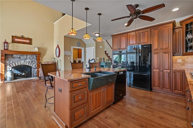 361 Patriot Ln, Economy, PA 15042 - kitchen featuring black appliances, a sink, a fireplace, brown cabinets, and light stone counters