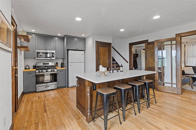 952 Jackman Ave, Avalon, PA 15202 - kitchen with stainless steel appliances, light wood-type flooring, light countertops, gray cabinets, and a breakfast bar