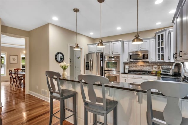 104 Southridge Dr, Cranberry Twp, PA 16066 - kitchen with stainless steel appliances, decorative backsplash, glass insert cabinets, a breakfast bar area, and wood finished floors