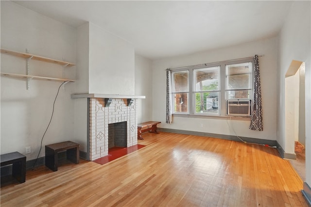 342 E 11th Ave, Homestead, PA 15120 - unfurnished living room featuring wood finished floors, cooling unit, a brick fireplace, and baseboards