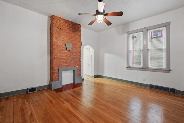 342 E 11th Ave, Homestead, PA 15120 - unfurnished living room featuring a fireplace, wood-type flooring, ceiling fan, arched walkways, and baseboards
