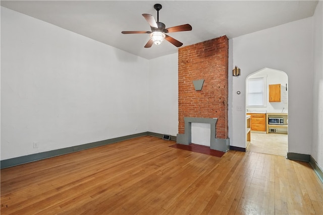 342 E 11th Ave, Homestead, PA 15120 - unfurnished living room with a brick fireplace, a ceiling fan, light wood-type flooring, and baseboards