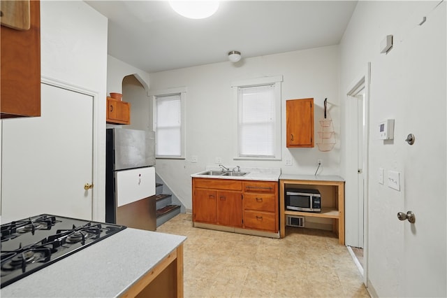 342 E 11th Ave, Homestead, PA 15120 - kitchen with appliances with stainless steel finishes, brown cabinetry, light countertops, and a sink