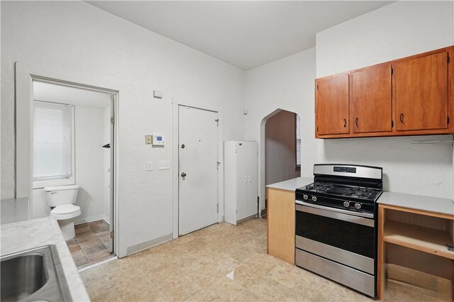 342 E 11th Ave, Homestead, PA 15120 - kitchen with stainless steel gas stove, light countertops, arched walkways, brown cabinetry, and a sink