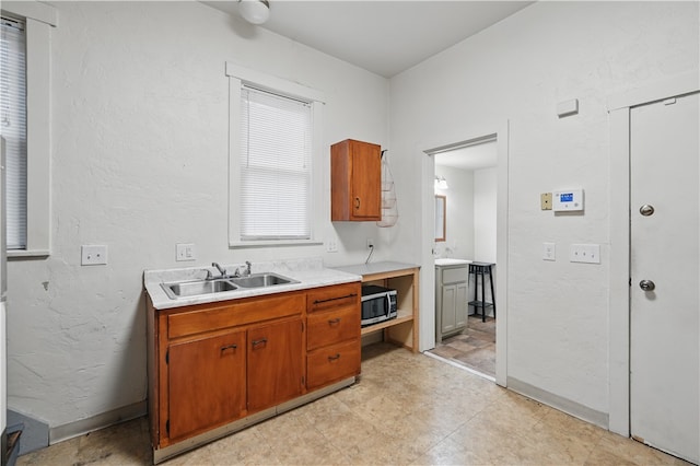 342 E 11th Ave, Homestead, PA 15120 - kitchen with a sink, light countertops, stainless steel microwave, brown cabinetry, and a textured wall