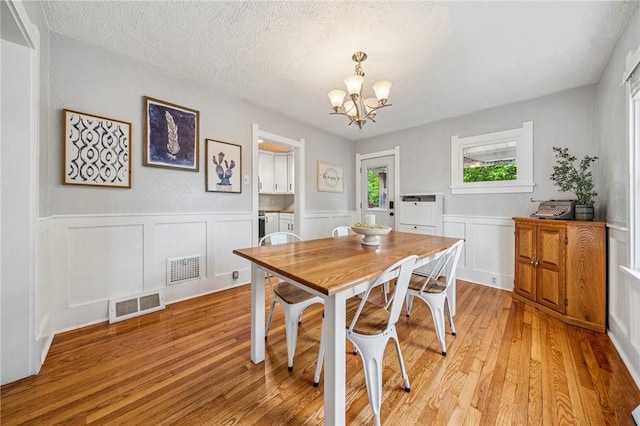 510 Central Ave E, Washington Boro, PA 15301 - dining space featuring a chandelier, light wood-style floors, a wainscoted wall, a textured ceiling, and a decorative wall