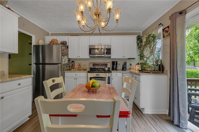 125 Spruce St, Brighton Twp, PA 15009 - kitchen featuring appliances with stainless steel finishes, a chandelier, white cabinetry, light wood-style floors, and tasteful backsplash