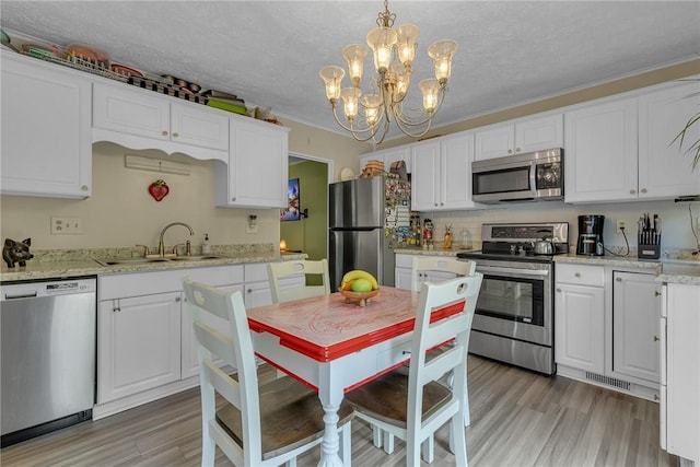 125 Spruce St, Brighton Twp, PA 15009 - kitchen with appliances with stainless steel finishes, a sink, a chandelier, white cabinetry, and light wood-style floors
