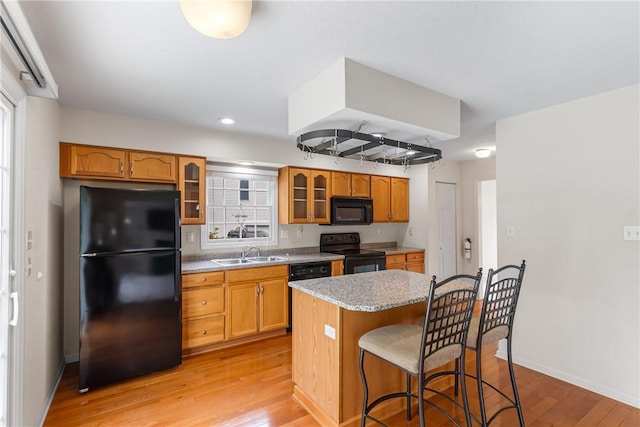 117 Trailside Ct, North Fayette, PA 15108 - kitchen with black appliances, a sink, a breakfast bar area, light wood-type flooring, and glass insert cabinets