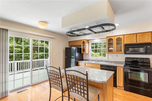 117 Trailside Ct, North Fayette, PA 15108 - kitchen with black appliances, a sink, a breakfast bar, light wood-style flooring, and glass insert cabinets
