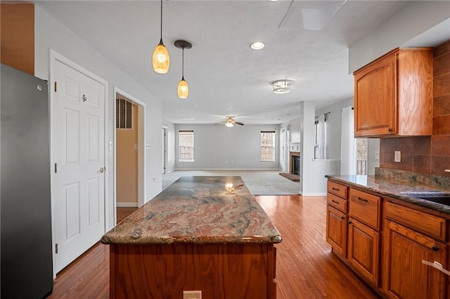115 Tartan Dr, Hempfield Twp Wml, PA 15601 - kitchen with freestanding refrigerator, open floor plan, wood finished floors, brown cabinets, and decorative backsplash