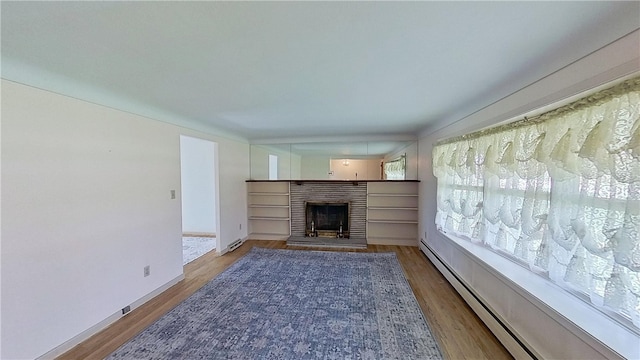 122 Burke Dr, Monroeville, PA 15146 - unfurnished living room featuring baseboard heating, wood finished floors, a fireplace, and baseboards