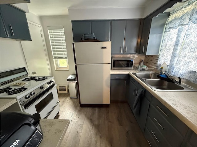3121 Crab Hollow Rd, Penn Hills, PA 15235 - kitchen with white appliances, a sink, wood finished floors, light countertops, and tasteful backsplash
