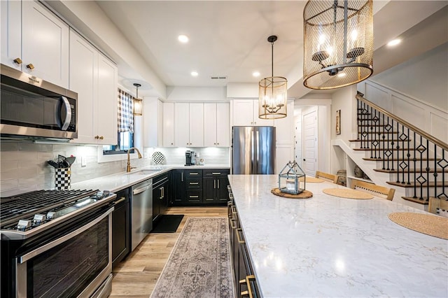 1006 Sweetgum Ct, Penn Twp Wml, PA 15644 - kitchen featuring stainless steel appliances, a chandelier, dark cabinetry, white cabinets, and light wood finished floors