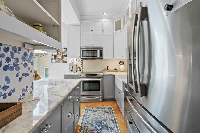 6015 Walnut St Unit 201, Shadyside, PA 15206 - kitchen with appliances with stainless steel finishes, gray cabinetry, light stone countertops, backsplash, and white cabinets
