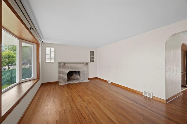 3353 Mcroberts Rd, Castle Shannon, PA 15234 - unfurnished living room featuring arched walkways, wood finished floors, a fireplace, and baseboards