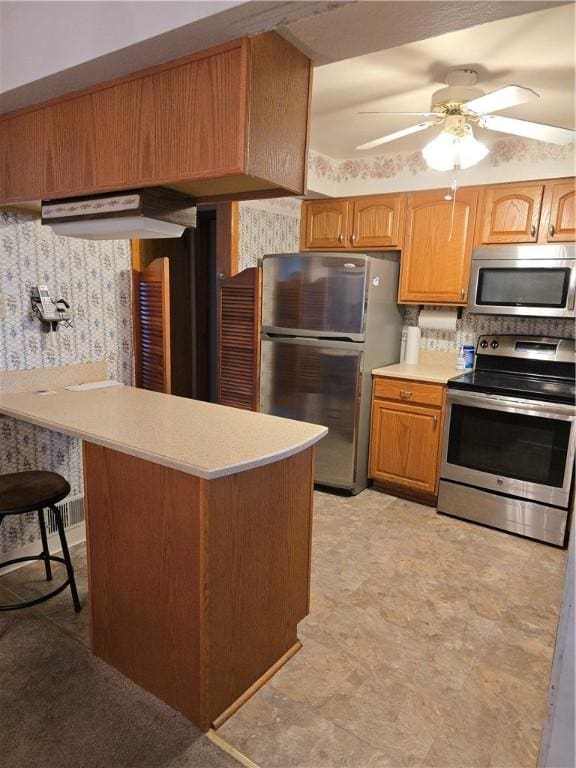 209 Pawnee St, Rostraver, PA 15012 - kitchen with stainless steel appliances, light countertops, wallpapered walls, ceiling fan, and a peninsula