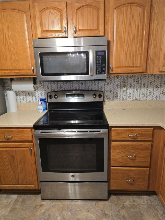 209 Pawnee St, Rostraver, PA 15012 - kitchen with stainless steel appliances, light countertops, and brown cabinetry
