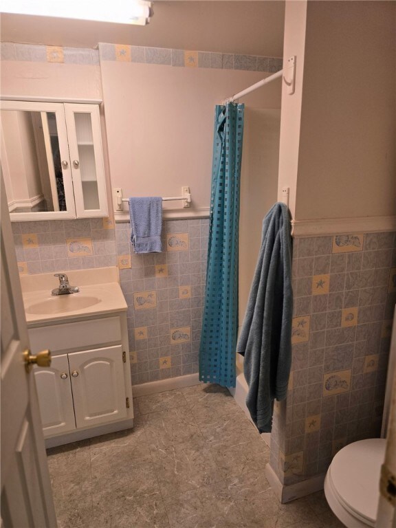 209 Pawnee St, Rostraver, PA 15012 - bathroom with tile walls, vanity, toilet, curtained shower, and a wainscoted wall