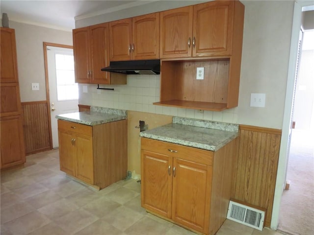 21 Daisytown Rd, W Pike Run Twp, PA 15427 - kitchen with under cabinet range hood, wainscoting, wooden walls, brown cabinetry, and backsplash
