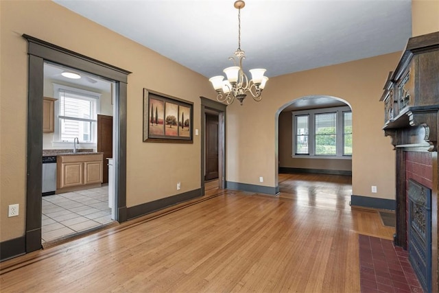 2938 Voelkel Ave, Dormont, PA 15216 - unfurnished dining area featuring arched walkways, a fireplace with flush hearth, a sink, light wood-style floors, and a chandelier