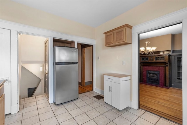 2938 Voelkel Ave, Dormont, PA 15216 - kitchen with freestanding refrigerator, light tile patterned flooring, a chandelier, and a fireplace