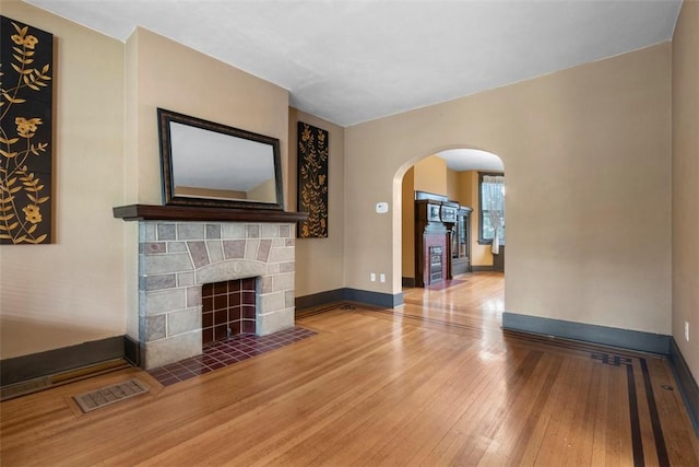 2938 Voelkel Ave, Dormont, PA 15216 - unfurnished living room featuring a fireplace with flush hearth, arched walkways, hardwood / wood-style floors, and baseboards