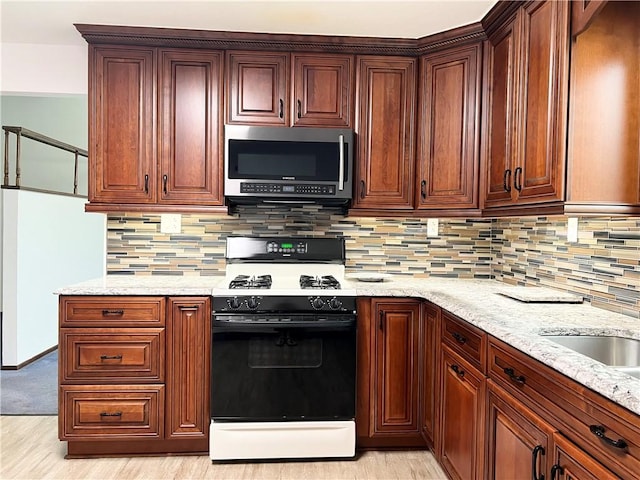 4130 James Dr, Lower Burrell, PA 15068 - kitchen with stainless steel microwave, white range with gas stovetop, decorative backsplash, light stone countertops, and light wood-style flooring