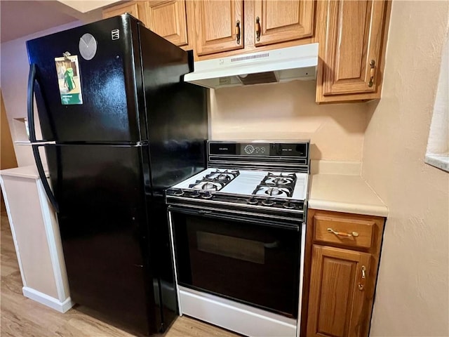 3329 Recker Dr, Baldwin Boro, PA 15227 - kitchen with range with gas cooktop, under cabinet range hood, freestanding refrigerator, light wood-style flooring, and light countertops
