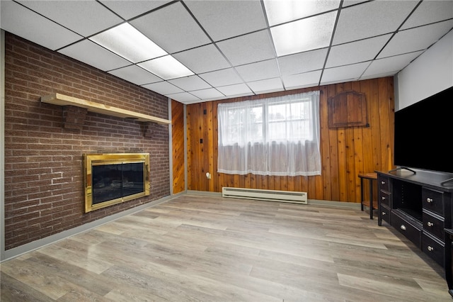 174 Hague Ln, South Union Twp, PA 15401 - unfurnished living room featuring a baseboard heating unit, a brick fireplace, wood finished floors, a paneled ceiling, and wood walls