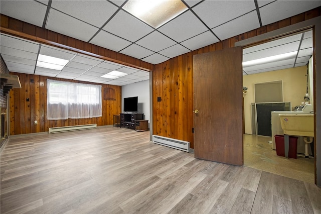 174 Hague Ln, South Union Twp, PA 15401 - unfurnished living room featuring a baseboard heating unit, wooden walls, wood finished floors, a paneled ceiling, and a sink