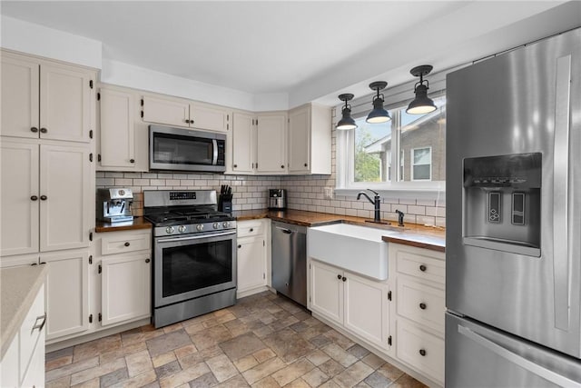 6032 Dalmation Dr, Bethel Park, PA 15102 - kitchen featuring appliances with stainless steel finishes, a sink, wood counters, backsplash, and light stone finish floors