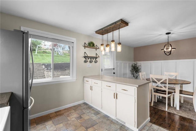 6032 Dalmation Dr, Bethel Park, PA 15102 - kitchen with freestanding refrigerator, a peninsula, white cabinetry, pendant lighting, and wainscoting