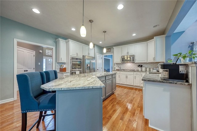 1517 Lombard Cir, South Strabane, PA 15301 - kitchen featuring appliances with stainless steel finishes, white cabinets, tasteful backsplash, a center island, and light stone counters