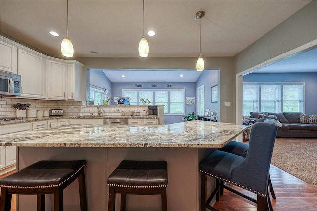 1517 Lombard Cir, South Strabane, PA 15301 - kitchen featuring stainless steel appliances, open floor plan, a breakfast bar, white cabinetry, and light stone countertops