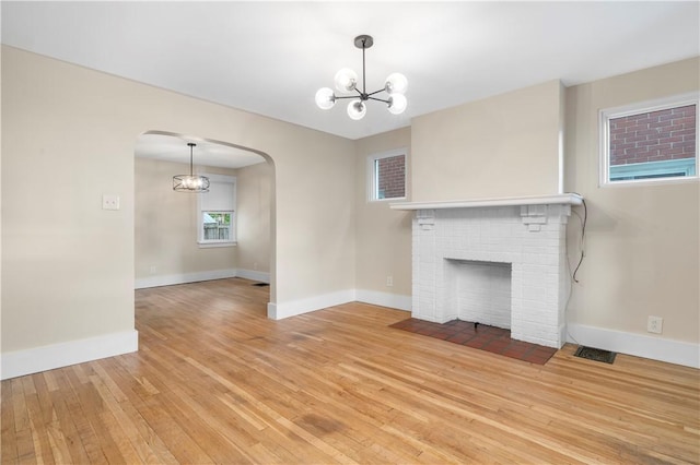 1727 Morningside Ave, Morningside, PA 15206 - unfurnished living room featuring arched walkways, a chandelier, light wood finished floors, baseboards, and a brick fireplace